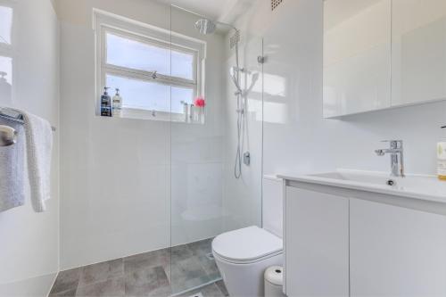 Miracle Miranda Sydney Apartment في ميراندا: حمام ابيض مع مرحاض ومغسلة