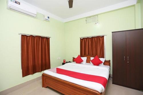 a bedroom with a bed with red pillows on it at Hotel Somnath Guest House ! Puri in Puri