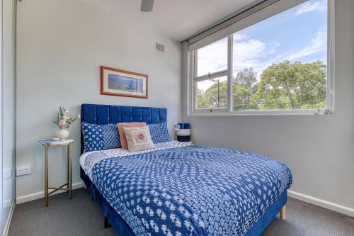 Miracle Miranda Sydney Apartment في ميراندا: غرفة نوم بسرير ازرق ونافذة