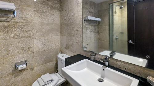 een badkamer met een wastafel, een toilet en een spiegel bij Grand Zuri Pematangsiantar in Pematangsiantar