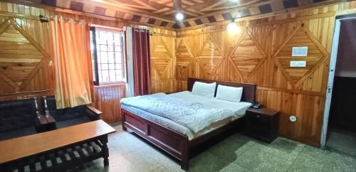 1 dormitorio con 1 cama y pared de madera en Sukoon- A Lake view BnB en Nainital