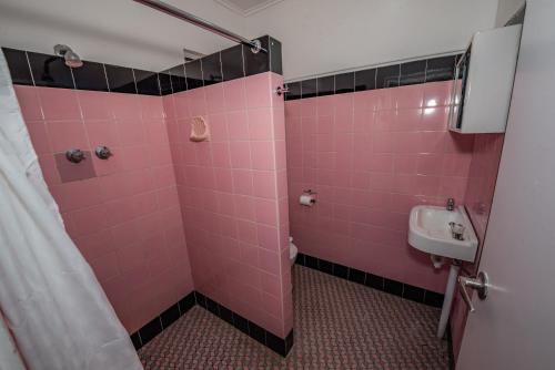 a pink bathroom with a sink and a shower at The Centennial Hotel Gulgong in Gulgong