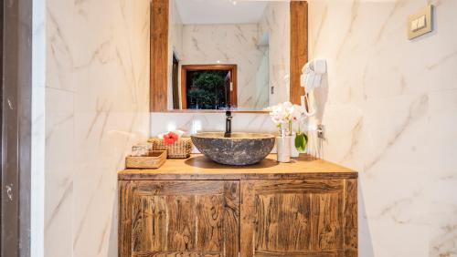 a bathroom with a stone sink and a mirror at Kirani Joglo Villa Bali by Mahaputra in Sukawati