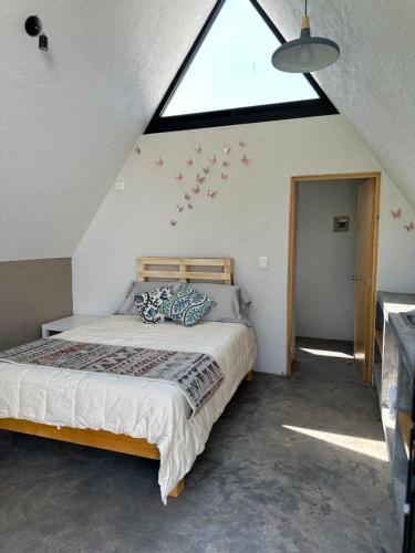 a bedroom with a bed and a large window at Chalets Encino Saúco in Malinalco