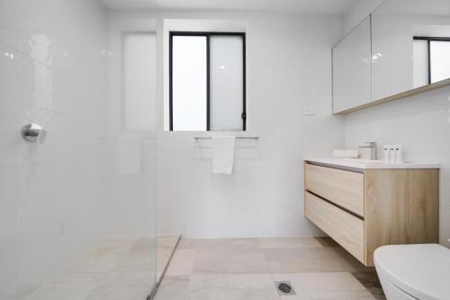 a white bathroom with a sink and a toilet at Spacious 4-bed Family Home in Tranquil Setting in Canberra