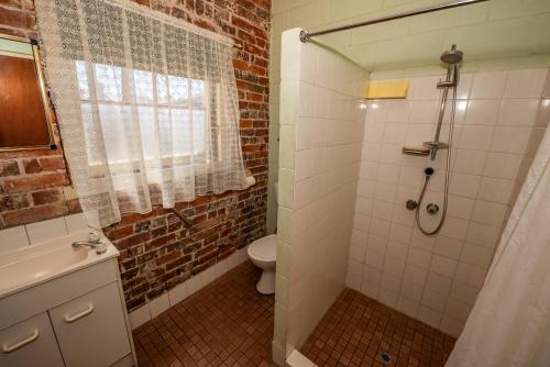 a bathroom with a shower and a toilet and a window at The Centennial Hotel Gulgong in Gulgong
