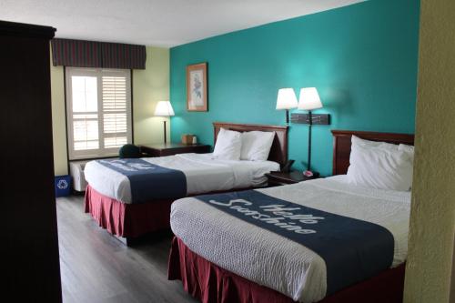 2 camas en una habitación de hotel con paredes azules en Days Inn by Wyndham Marianna, en Marianna