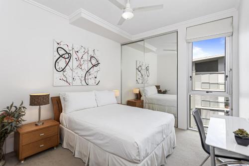 um quarto com uma cama, uma secretária e uma janela em High-Floor 2-Bed CBD Unit With Views & Amenities em Brisbane