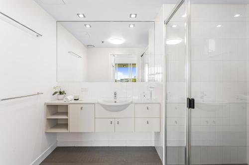 a white bathroom with a sink and a shower at High-Floor 2-Bed CBD Unit With Views & Amenities in Brisbane