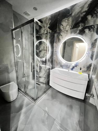 uma casa de banho com um chuveiro, um lavatório e um espelho. em London House Apartment em Baku