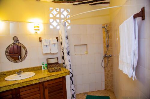 uma casa de banho com um lavatório e um chuveiro em Charming 1-Bed Cottage in Diani Beach 10min to bea em Diani Beach
