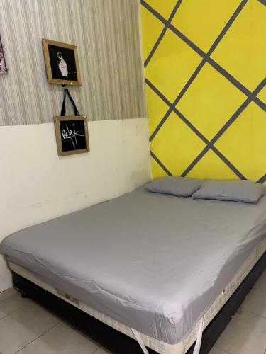 Cama en habitación con pared amarilla y blanca en Villa ERICK Batu dekat Jatimpark 2, en Tlekung
