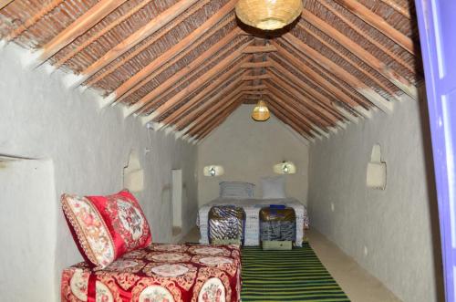 - une chambre avec un lit et une chaise dans l'établissement AUBERGE El HAJ BOUAYYADY ZOUAKINE, 