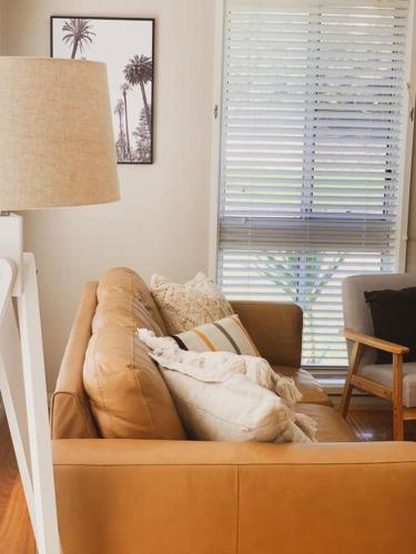 a leather couch in a living room with a lamp at DUNES Anna Bay, house close to beach, big yard in Anna Bay