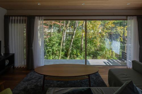 ein Wohnzimmer mit einem Tisch und einem großen Fenster in der Unterkunft Hotel Sengokuhara 533 in Hakone