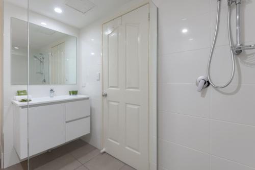 a white bathroom with a shower and a sink at The Newport on Macrossan - Adults Only in Port Douglas