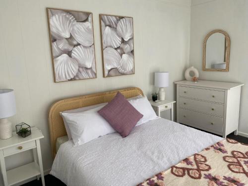 een slaapkamer met een bed met drie foto's aan de muur bij Mars and Venus in Venus Bay
