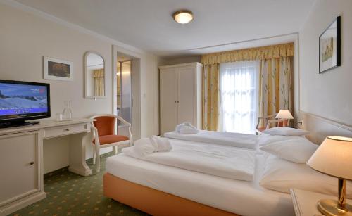 a hotel room with a large bed and a television at Hotel Waldheim Garni in Mayrhofen