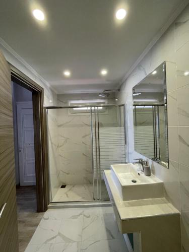 uma casa de banho com um chuveiro, um lavatório e um espelho. em Horizon em Pefkohori