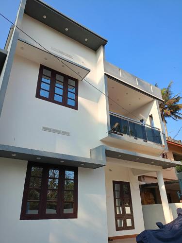 a white house with a balcony on top of it at Enna homestay in Varkala