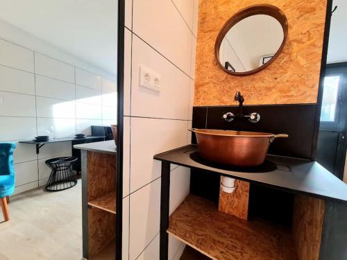 La salle de bains est pourvue d'un lavabo en cuivre et d'un miroir. dans l'établissement Studio indépendant avec jardin privatif, à Fontenay-aux-Roses