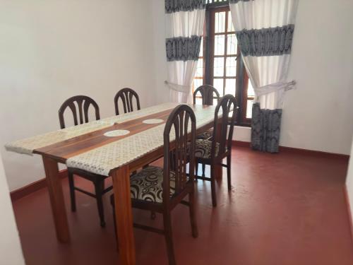 uma sala de jantar com uma mesa e cadeiras e uma janela em Relax Home Pinnawala em Rambukkana