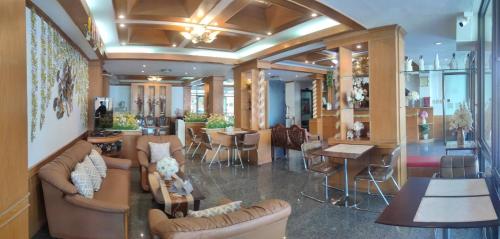 a lobby with couches and tables and a restaurant at โรงแรมอารีน่ารีสอร์ท อุตรดิตถ์ in Uttaradit
