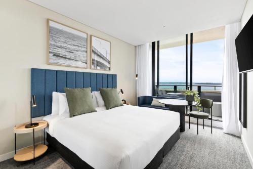 a bedroom with a large bed and a large window at Quest Woolooware Bay in Cronulla