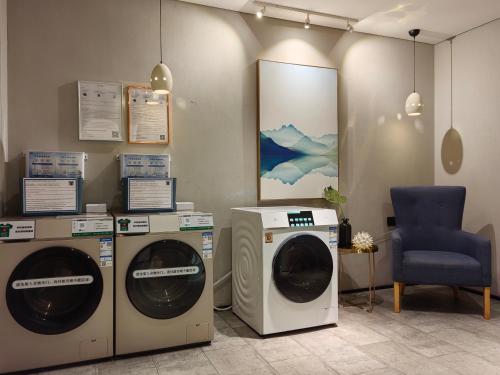 a laundry room with two washing machines and a chair at Waito Hotel Yuexiu Park Guangzhou in Guangzhou
