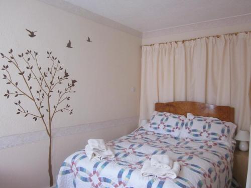 a bedroom with a bed and a tree on the wall at Kendoon Apartment in Kippford