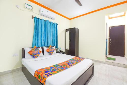 a bedroom with a bed with colorful sheets and a window at FabExpress Shanel Beachside Resort in Baga