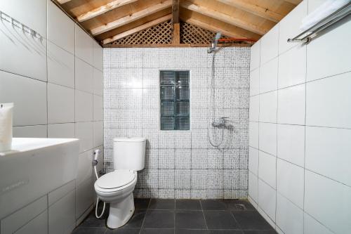 a white bathroom with a toilet and a shower at OYO 2393 Putroyono Homestay in Magelang