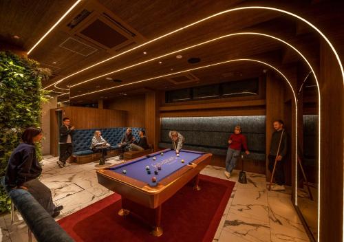 a pool table in a room with people sitting at HOTEL GRAPHY Shibuya in Tokyo