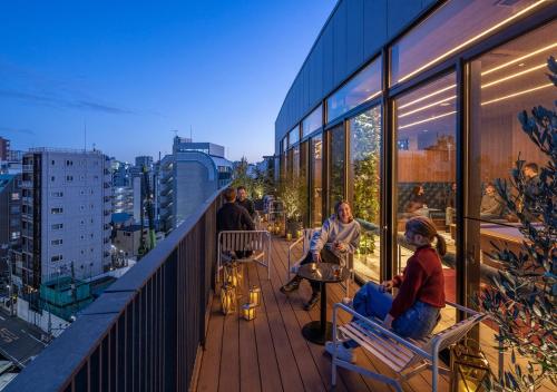 un grupo de personas sentadas en un balcón de un edificio en HOTEL GRAPHY Shibuya en Tokio