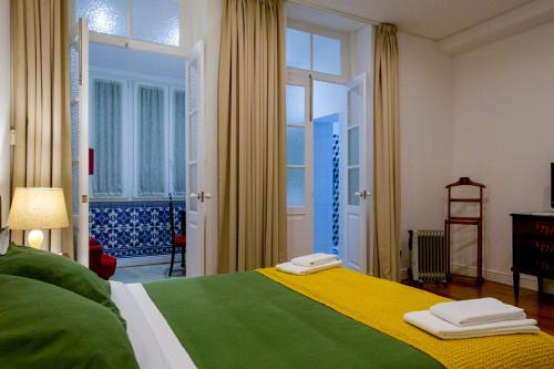 a bedroom with a green and yellow bed and a window at Casa Velha Guesthouse in Porto