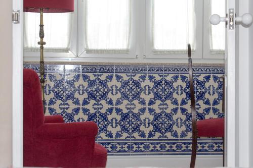 a living room with a red chair and blue and white tiles at Casa Velha Guesthouse in Porto