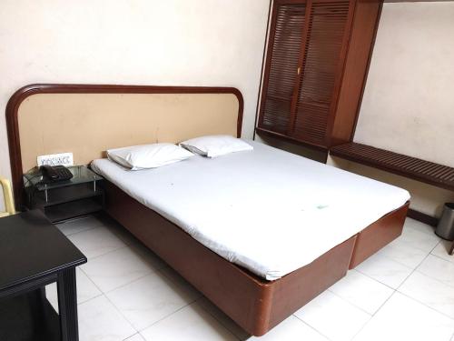 a bedroom with a bed with white sheets and pillows at Hotel Diana Gandhipuram in Coimbatore