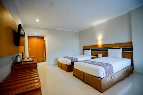 a hotel room with two beds and a television at Cakra Kembang Hotel in Yogyakarta