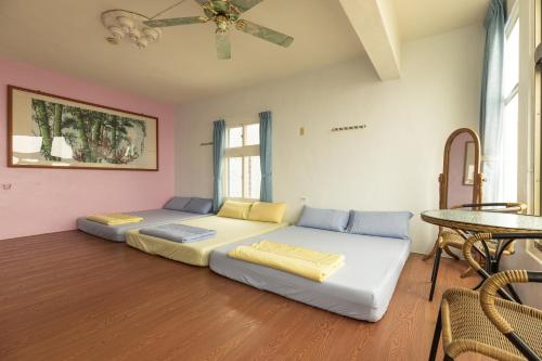 1 dormitorio con 2 camas y ventilador de techo en Jinshawan B&B, en Magong