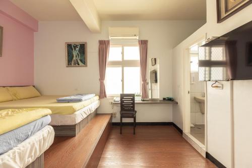 una camera da letto con due letti e una scrivania con una sedia di Jinshawan B&B a Magong
