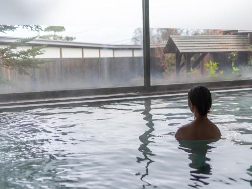 a man sitting in a pool of water at Kusatsu-onsen Hotel Resort in Kusatsu