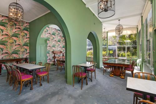 um restaurante com paredes verdes, mesas e cadeiras em Victoria and Albert Guesthouse em Mount Victoria