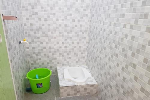 een badkamer met een toilet en een groene emmer bij OYO 93771 Sejolie Sibayak in Berastagi