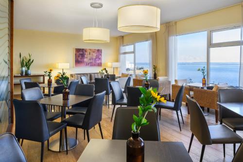 a dining room with tables and chairs and windows at Nevo by Isrotel Collection in Ein Bokek