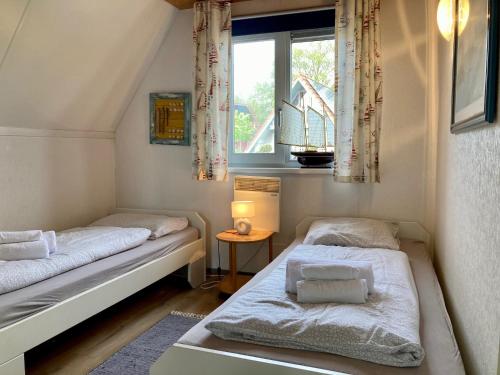 two beds in a small room with a window at Urlaubsruhe 6 Pers Holiday home w terrace close to National Park Lauwersmeer in Anjum