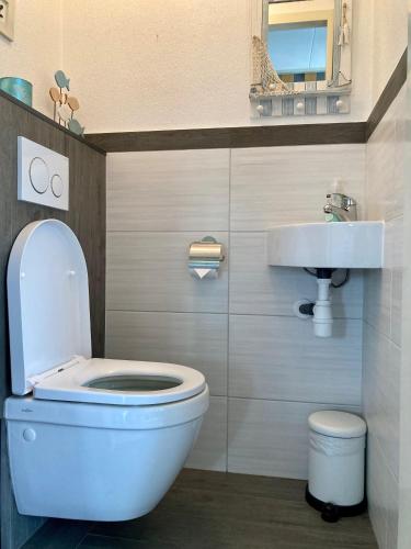 a bathroom with a white toilet and a sink at Urlaubsruhe 6 Pers Holiday home w terrace close to National Park Lauwersmeer in Anjum