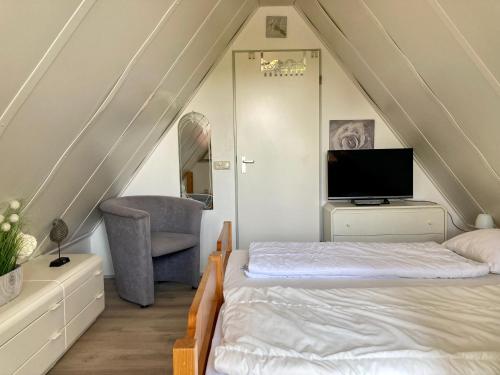 a attic bedroom with a bed and a chair at 4 pers. Holiday Home Petra with solarium in Anjum
