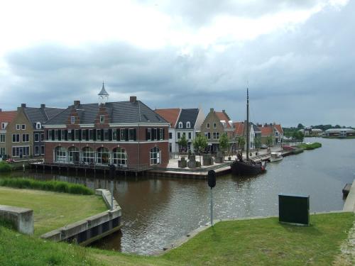a group of buildings next to a river with a boat at Urlaubsruhe 6 Pers Holiday home w terrace close to National Park Lauwersmeer in Anjum