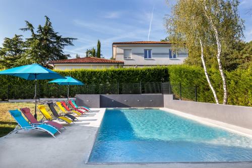 a pool with chairs and umbrellas next to a house at LE PALMIER in Coulounieix-Chamiers