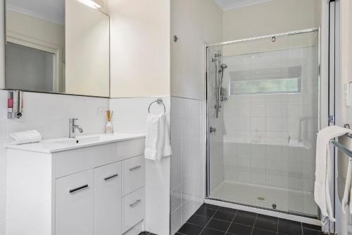 a white bathroom with a shower and a sink at Cottage on Chapman in Dover